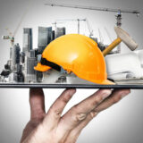 Image of hand holding up a platform with a hard hat, crane, and other construction related imagery